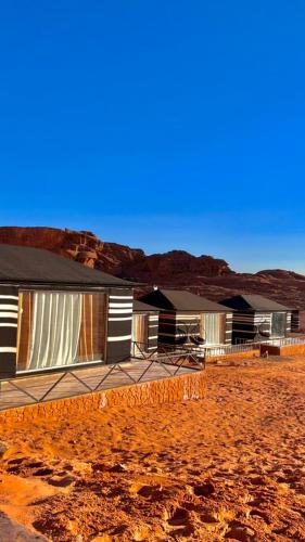 a row of houses in the desert with mountains in the background at RUM STARDUST lUXURY CAMP in Wadi Rum
