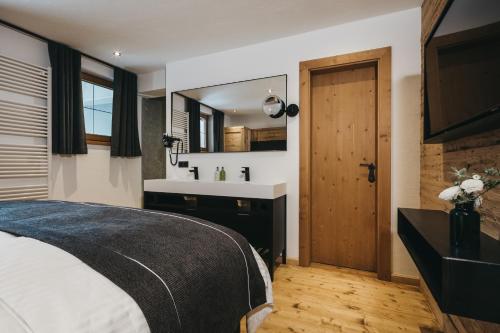 a bedroom with a bed and a sink and a mirror at VAYA Seefeld inklusive Seefeld Gästekarte in Seefeld in Tirol