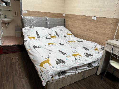a bed with a blanket with animals on it at Shinlong Happiness House in Tongluo