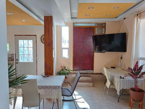 a dining room with two tables and a flat screen tv at PentHouse con Roof Garden Privado Aeropuerto CDMX in Mexico City