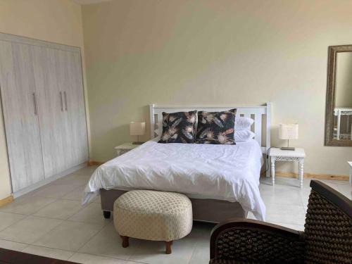 a bedroom with a large bed and a chair at Beacon Stay Beach Studio Apartment in Summerstrand