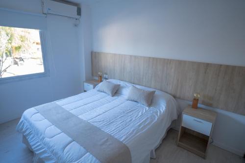 1 dormitorio con cama blanca y ventana en Santa Cecilia Boutique en Villa Carlos Paz