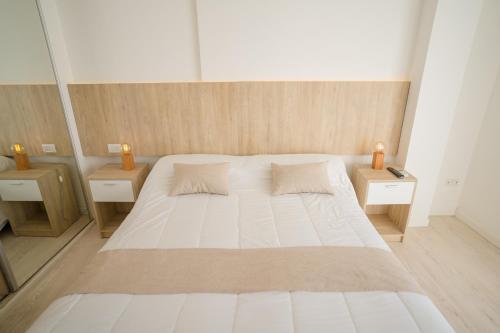 1 dormitorio con 1 cama blanca grande y 2 mesitas de noche en Santa Cecilia Boutique en Villa Carlos Paz
