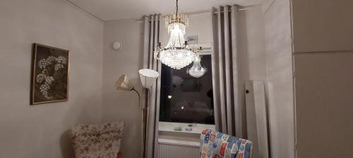 una lámpara de araña en una sala de estar con ventana en Båstad Stationsterrassen 7, en Båstad
