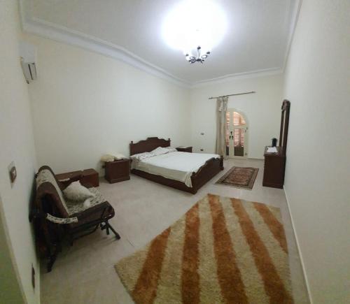 Villa elzaher في Qaryat Shākūsh: غرفة نوم بسرير واريكة وكرسي