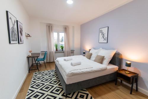 een slaapkamer met een bed, een tafel en een bureau bij DWELLSTAY - Wohnung 90qm, 3 Schlafzimmer, Küche, Wohnzimmer, Balkon, Netflix in Fulda