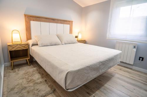 - une chambre avec un grand lit blanc et deux lampes dans l'établissement APARTAMENTO PEDRADOURO, à Malpica