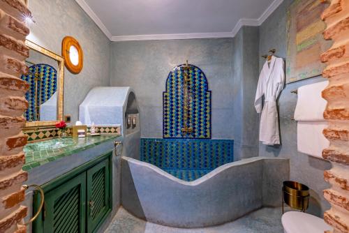 Maïpa Boutique Riad في مراكش: حمام مع حوض كبير ومغسلة
