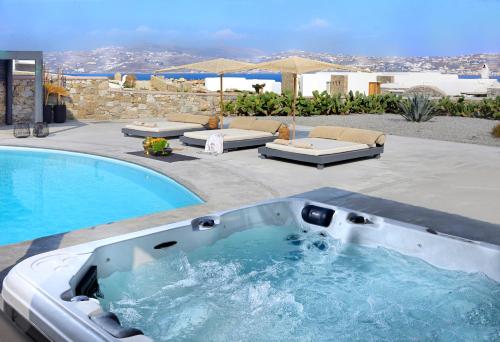 una piscina con bañera de hidromasaje junto a un patio en Tohu Villas Mykonos, en Ornos