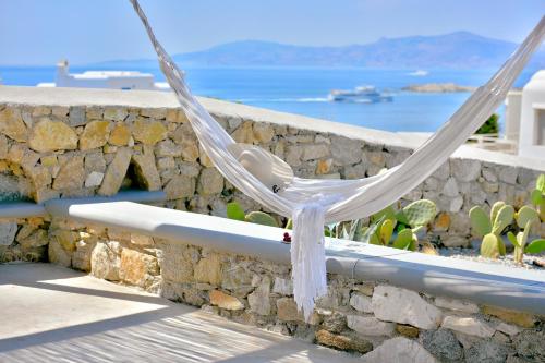 une chaise blanche assise sur une corniche avec un mur en pierre dans l'établissement Tohu Villas Mykonos, à Ornos