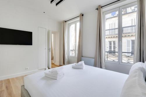 ein Schlafzimmer mit einem weißen Bett und einem großen Fenster in der Unterkunft Pick A Flat's Apartments in Opéra - Rue d'Hauteville in Paris