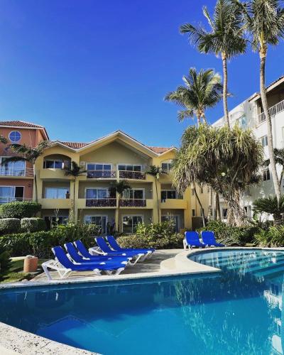 a resort with a swimming pool with chairs and palm trees at Agualina Kite Hotel Oceanfront Apartments in Cabarete