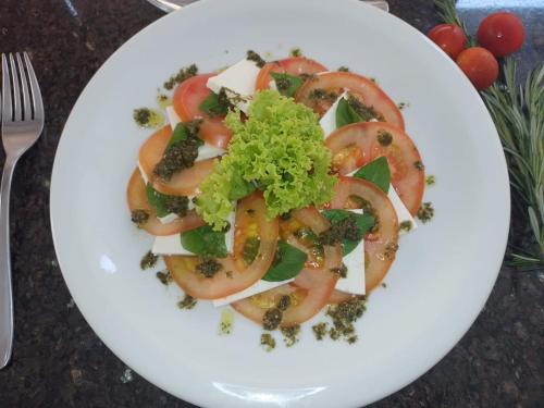 a white plate with a salad with tomatoes and broccoli at Pituba Praiamar Hotel in Salvador