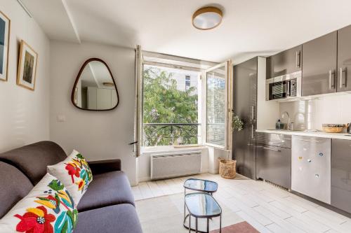 un salon avec un canapé et une fenêtre dans l'établissement Résidence Louvre - Bellan, à Paris