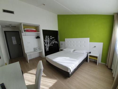a bedroom with a white bed and a green wall at Green Hotel Motel in Vergiate