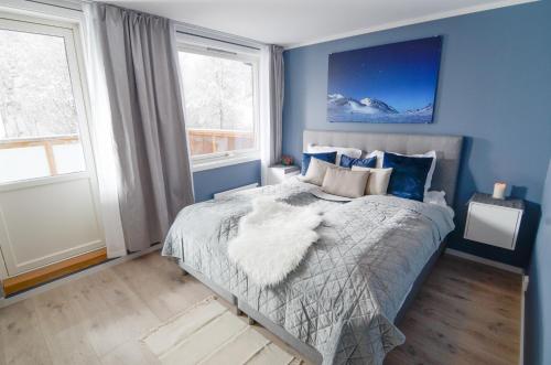 Haugetuft Apartments في Åmot: غرفة نوم مع سرير والجدران الزرقاء والنوافذ