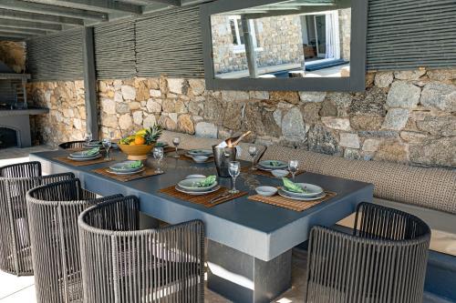 a blue table with chairs in a room with a stone wall at Tohu Villas Mykonos in Ornos