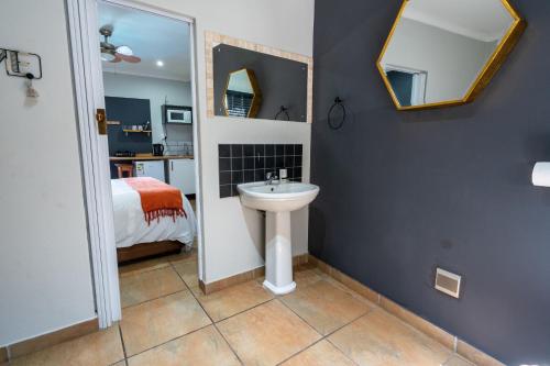 a bathroom with a sink and a bed and a mirror at Boma Lodge in Durban
