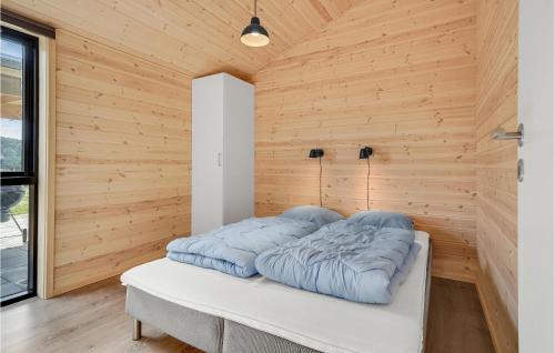 a bed in a room with a wooden wall at An Awesome Home In Storvorde With 4 Bedrooms And Wifi in Storvorde
