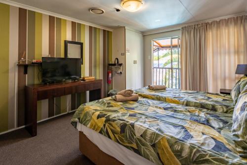 Una habitación de hotel con dos camas y un televisor de pantalla plana. en Boma Lodge, en Durban
