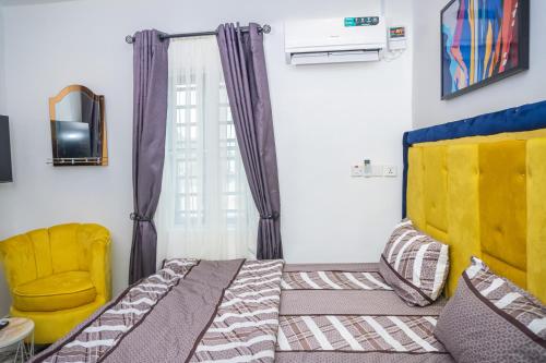 a bedroom with a bed and a yellow chair at Admirable 2-bed-Apt With Pool, 24hrs Power & Unlimited Internet in Amuwo