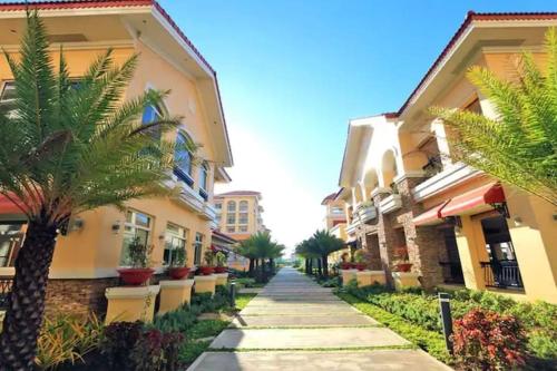 a walkway between two buildings with palm trees at 2BR Casa Mia Sanremo Oasis Cebu in Talisay