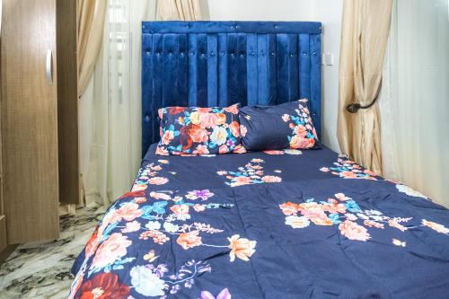 uma cama com uma cabeceira azul com flores em Live By The Water 2-Bed-Apt With FAST Wi-Fi And Secured em Amuwo