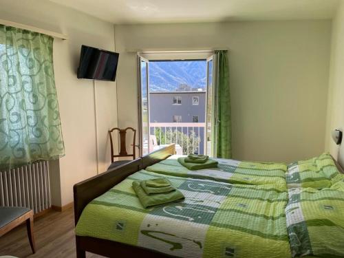 Un dormitorio con una cama con sábanas verdes y una ventana en Ristorante Gordolese con alloggio, en Gordola