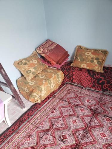 a pile of pillows sitting on a bed with a rug at El barandilla in Sidi Ifni