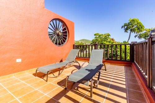 a balcony with two chairs and a wheel on the wall at Hotel Ecolife Tenerife in San Miguel de Abona