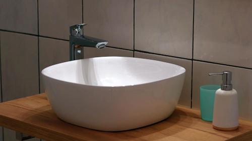 lavabo blanco con grifo en el baño en Le Cairn Chambres & Table d'hôtes, en Saint-Bonnet-en-Champsaur