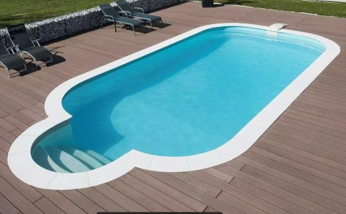 una piscina su una terrazza in legno con sedie intorno di Camping Du Paquier Fané a Chagny