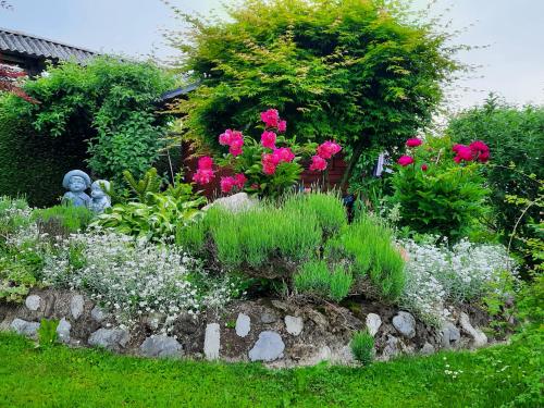 a garden with pink and white flowers and a statue at Garden Paradise Bled Apartments - garden, pond and castle view in Bled