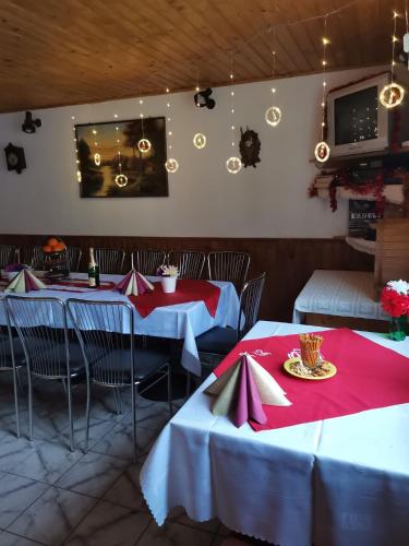 a restaurant with two tables with red and white tablecloths at Fontana erdélyi vendégház in Odorheiu Secuiesc