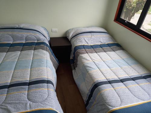 two beds sitting next to each other in a room at Cabañas y Departamentos Las Palmas, Temuco Depto 1 in Temuco