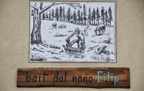 リヴィーニョにあるBait dal Nono Filipの雪上の男性像を壁面に掲げた看板