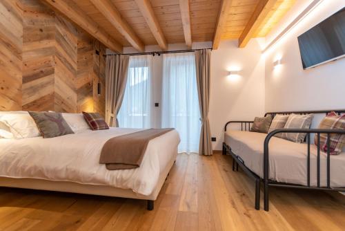 two beds in a bedroom with wooden walls and wooden floors at B&B El Lares - B&B L'Avez in Canale dʼAgordo