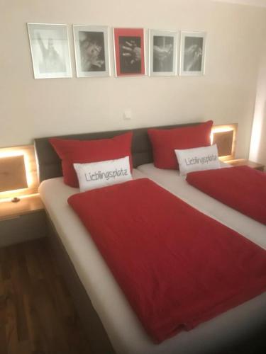 a bedroom with two beds with red pillows and pictures on the wall at Ferienwohnung Romantica EG in Schopfloch