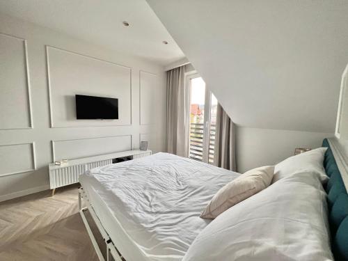 a white bedroom with a bed and a tv at Grand Apartament in Złotów