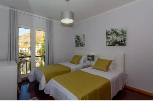 two beds in a room with a window at Praia Mar (sea view) by STAY Madeira Island in Ponta do Sol