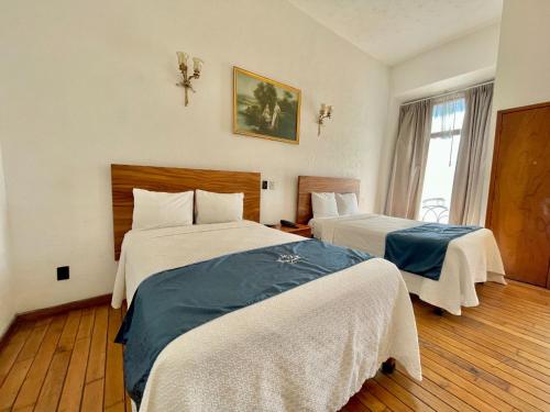 a hotel room with two beds and a window at Hotel Frances in Guadalajara