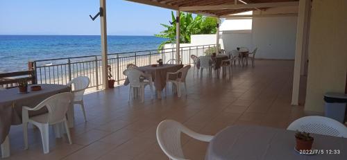 a restaurant with tables and chairs and the ocean at lemonishouse by the sea 2 in Nea Skioni