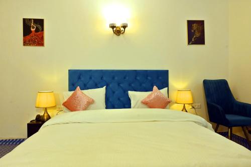 1 dormitorio con 1 cama con cabecero azul y 2 lámparas en Jay Ally - Boutique Hotel, en Nueva Delhi