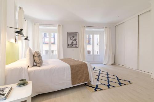 a white bedroom with a bed and a desk at Luminoso y amplio apartamento en Ópera in Madrid