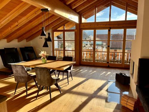 ein Esszimmer mit einem Tisch, Stühlen und Fenstern in der Unterkunft Wally Luxus Lodge im Ferienhaus Magdalena in Mittenwald