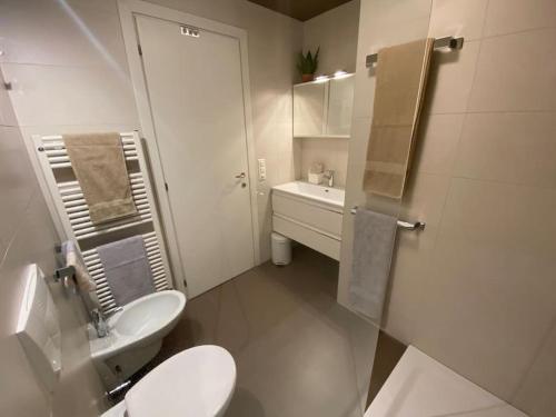 bagno bianco con servizi igienici e lavandino di Appartement am See mit Pool und Sauna a Melide