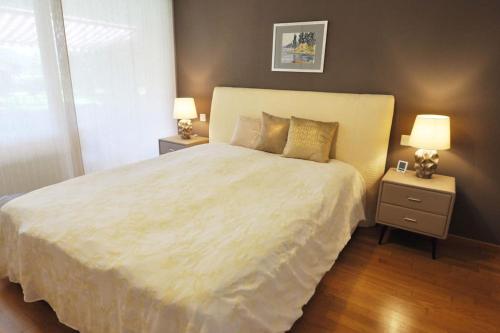una camera da letto con un grande letto bianco con due comodini di Appartement am See mit Pool und Sauna a Melide