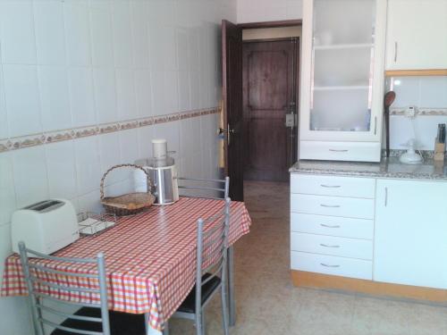 eine Küche mit einem Tisch, einem Tisch und einem Tisch sowie einer Küche in der Unterkunft Quartos no centro de Torres Vedras in Torres Vedras