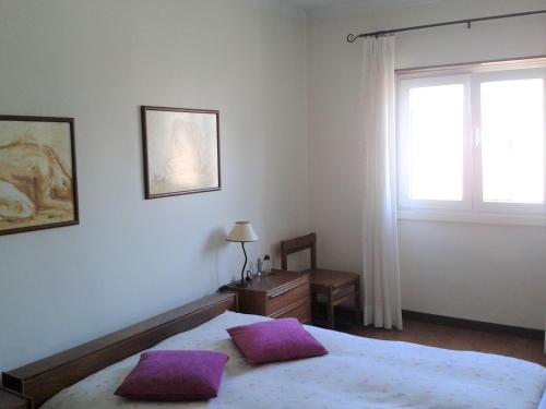 ein Schlafzimmer mit einem Bett mit lila Kissen darauf in der Unterkunft Quartos no centro de Torres Vedras in Torres Vedras