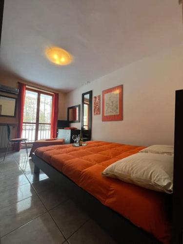 a bedroom with a large bed with an orange blanket at Calda e accogliente Limone in Limone Piemonte